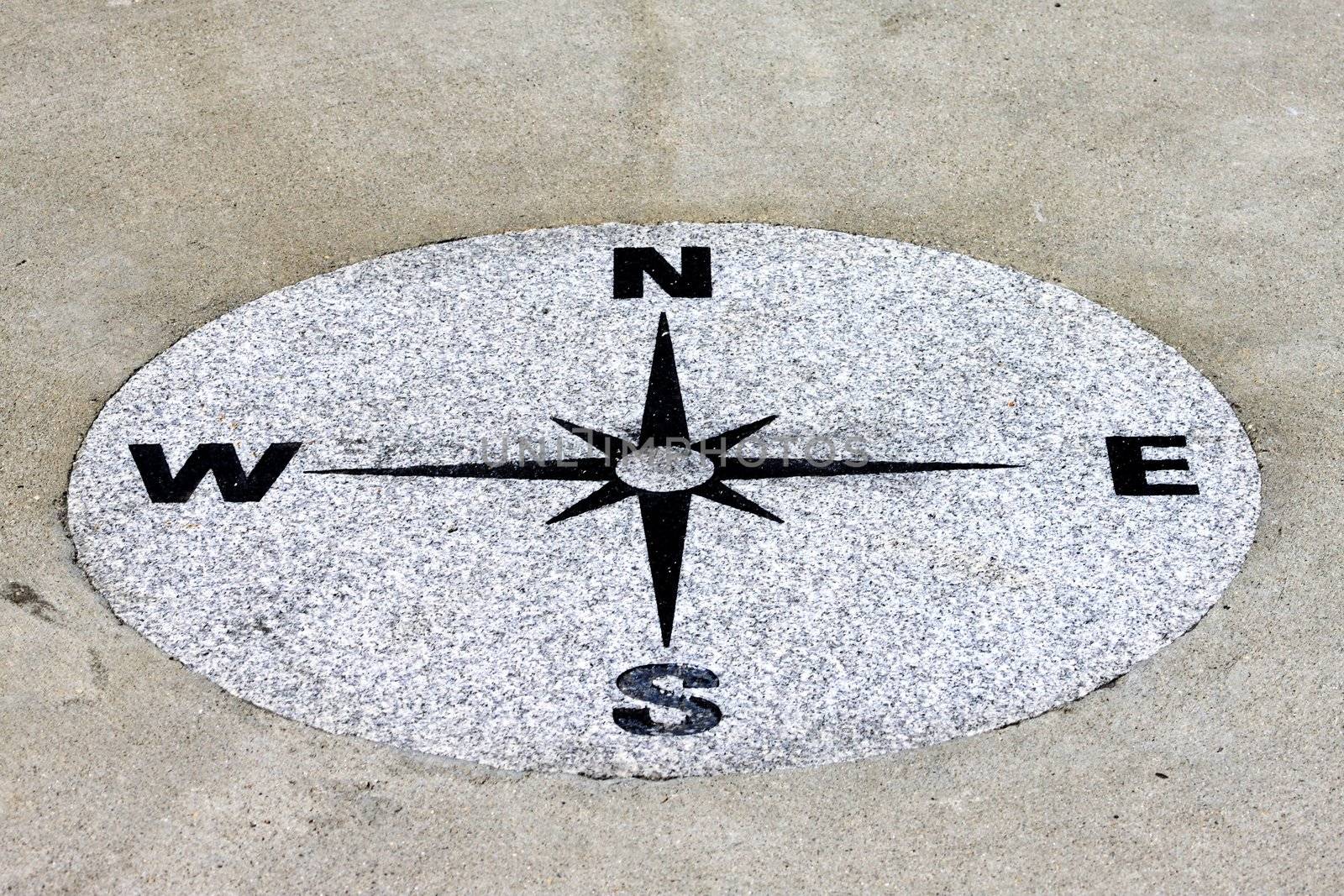 Compass found on a sidewalk on a granit background