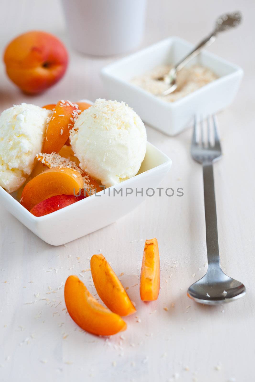 Freshly made coconut icecream with slices of apricot and roasted coconut