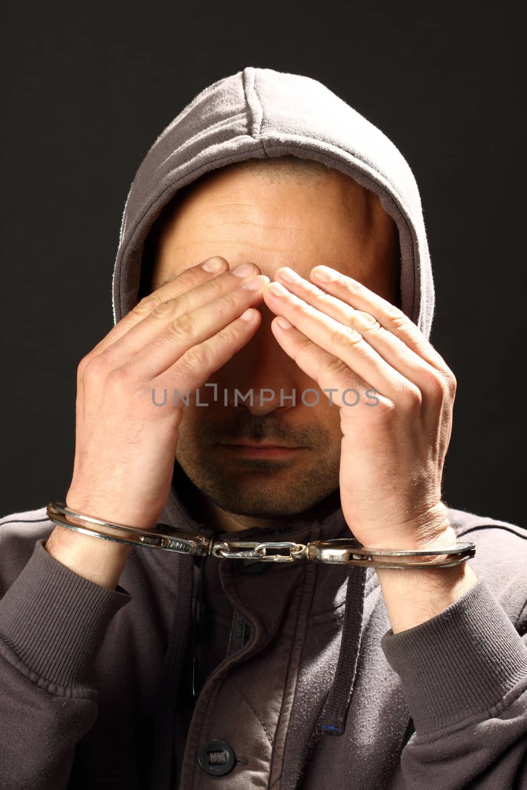 man with handcuffs, hiding his face 