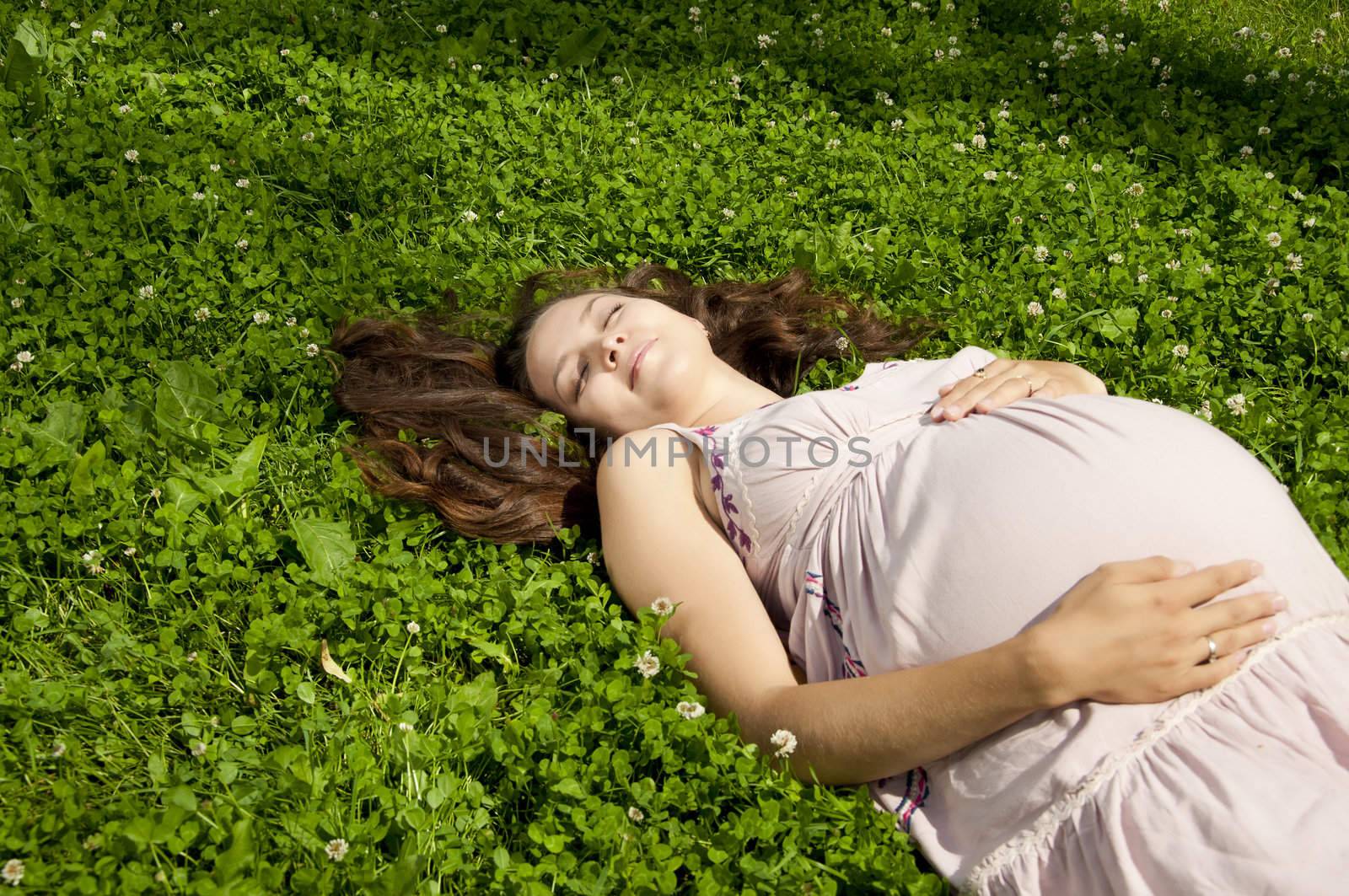 Beautiful pregnant woman relaxing in the summer park