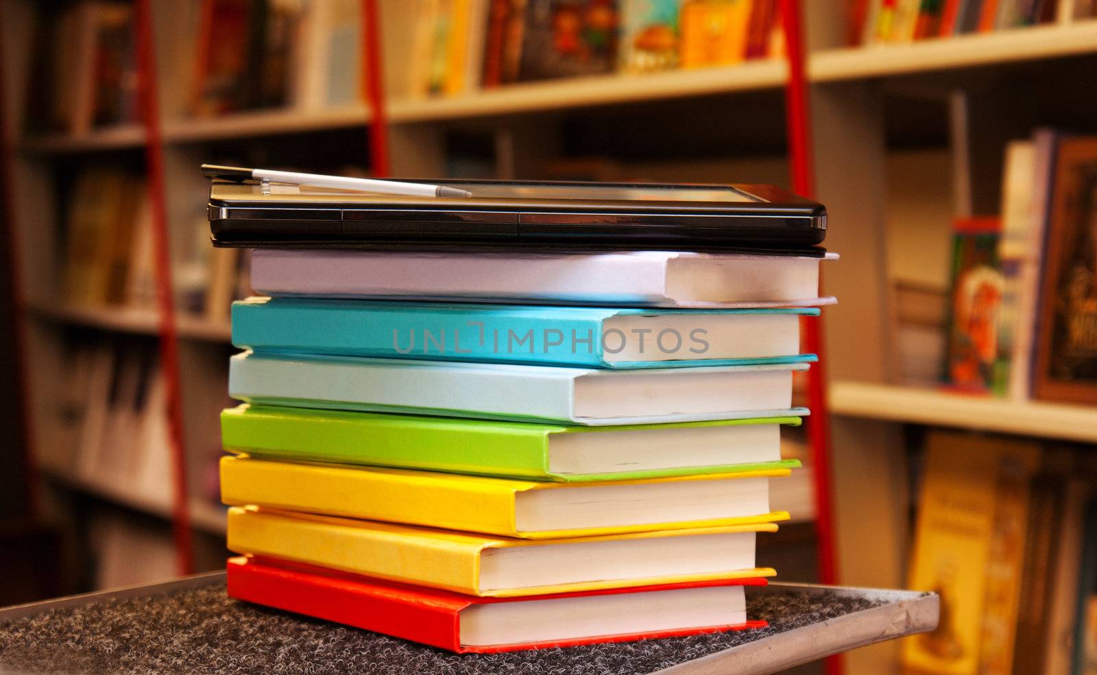 Stack of colorful books with electronic book reader by AndreyKr