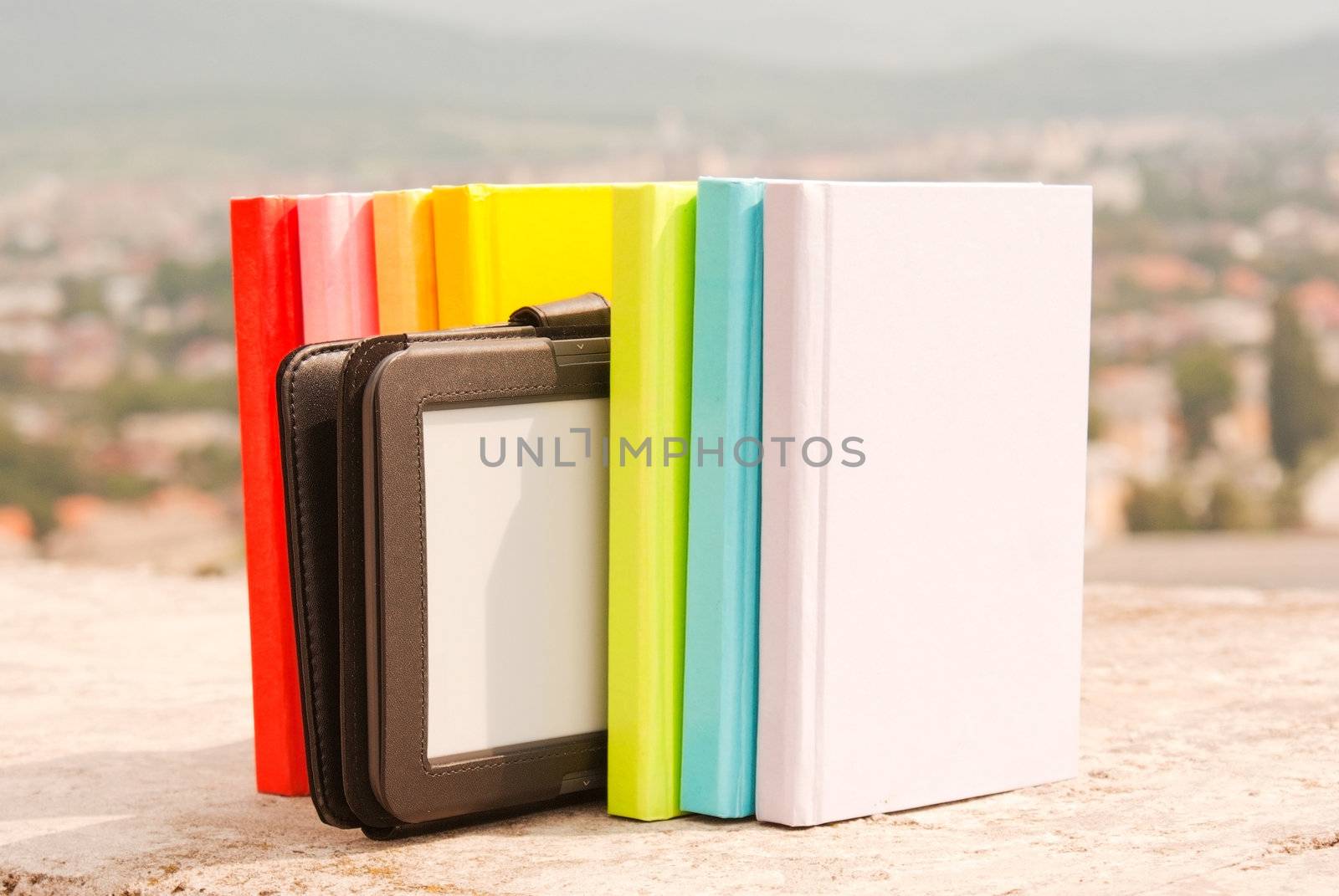 Row of colorful books with electronic book reader by AndreyKr