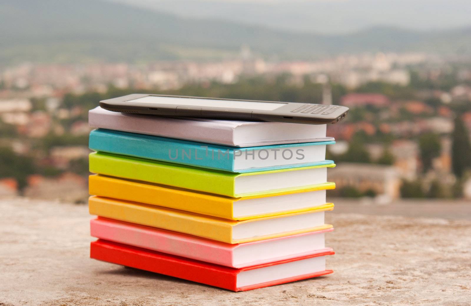 Stack of colorful books with electronic book reader