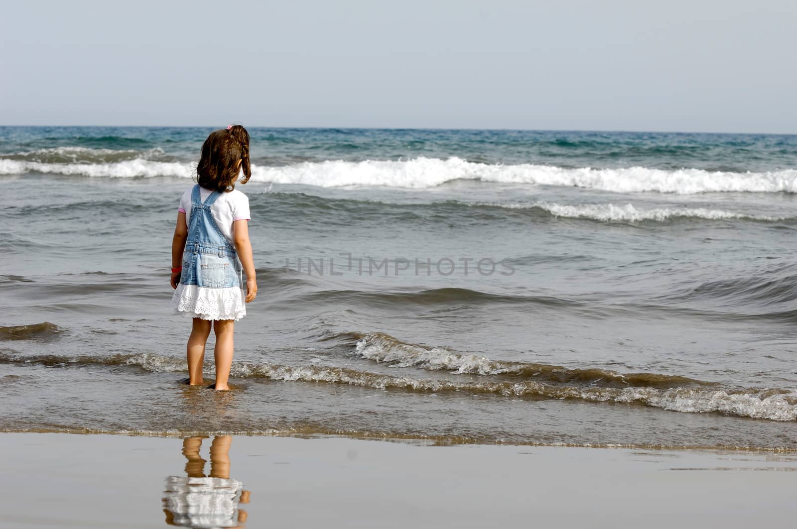 Child is standing in the ocean alone.