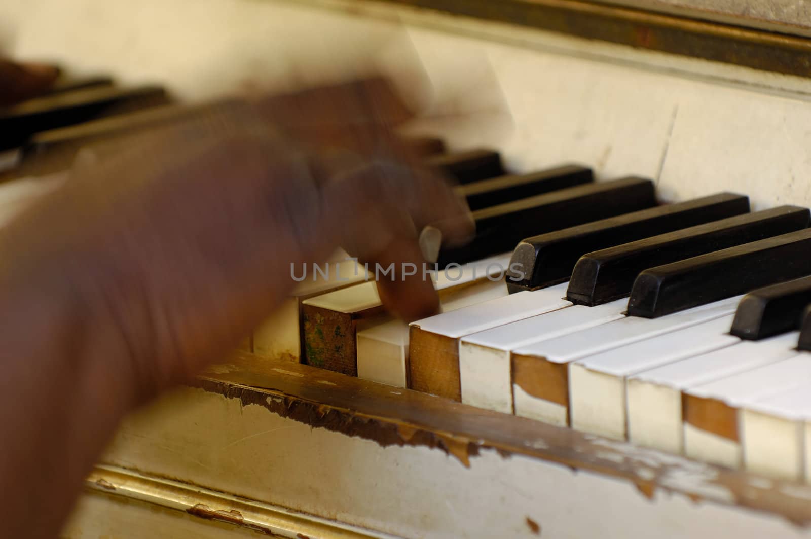 Musician is playing on a very old piano. Noate that the hand and fingers are in motion blur