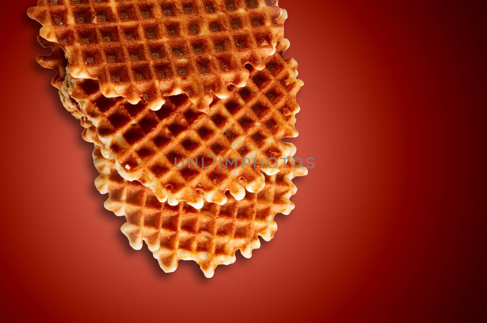 Fresh crisp waffles isolated on dark red background