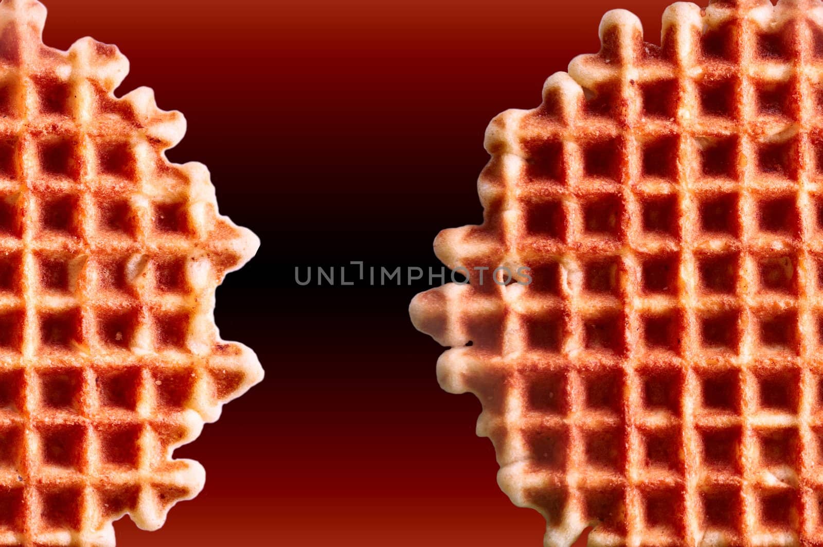 Fresh crisp waffles isolated on dark red background