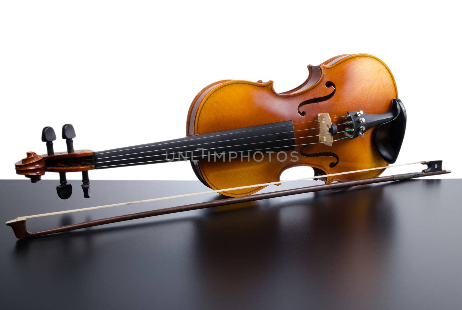 Violin on top of dark table partially isolated on white background.