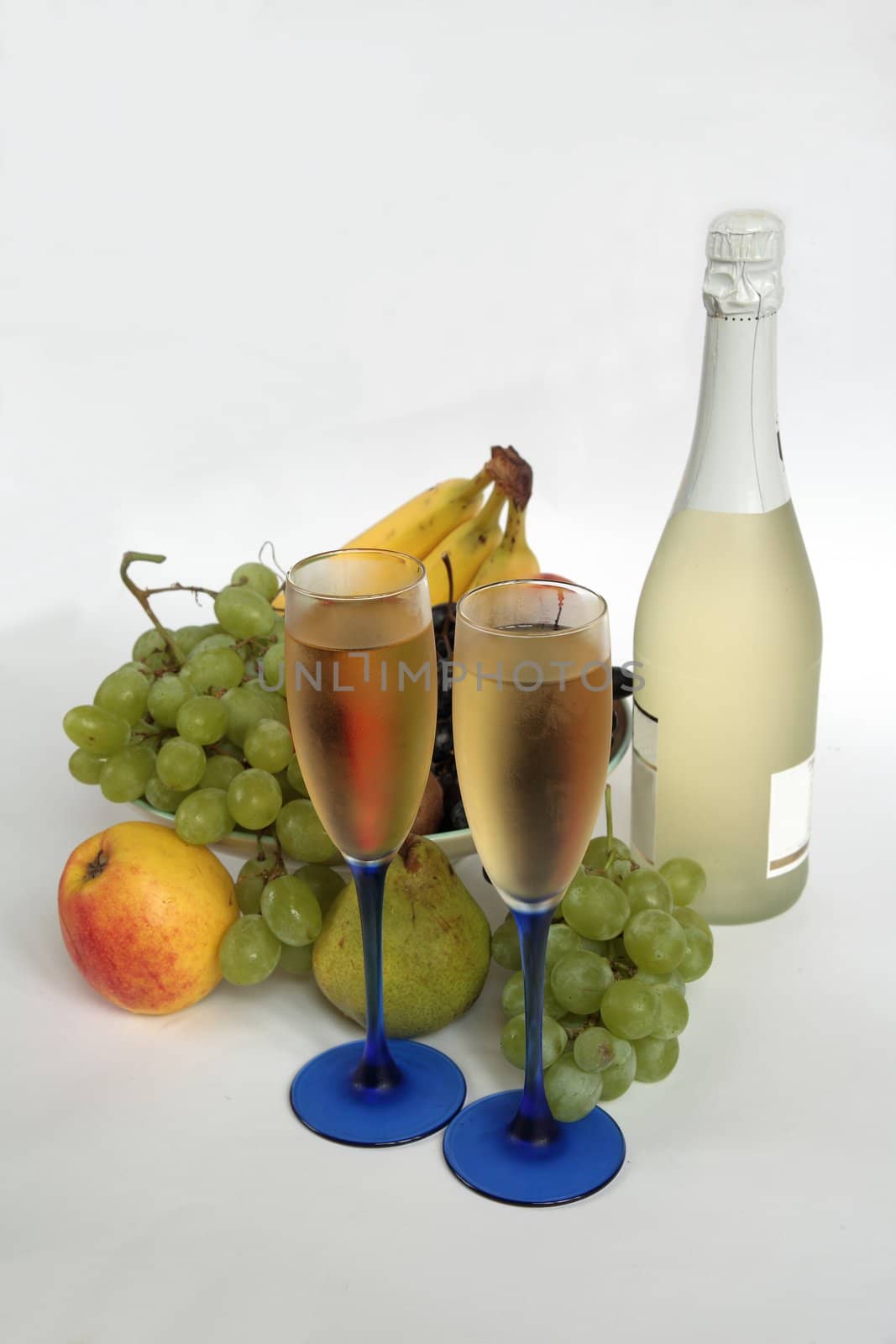 Champagne in glasses and fresh fruits; grapes,apples,pear and banana.