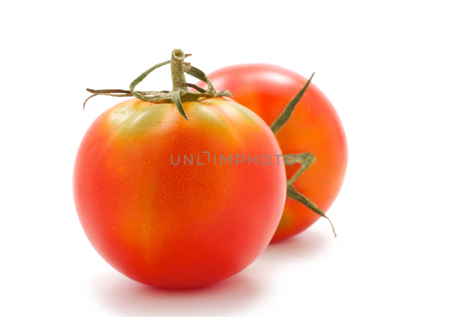 Two immature tomatoes with green tails. Small size. lie group. On a white background.