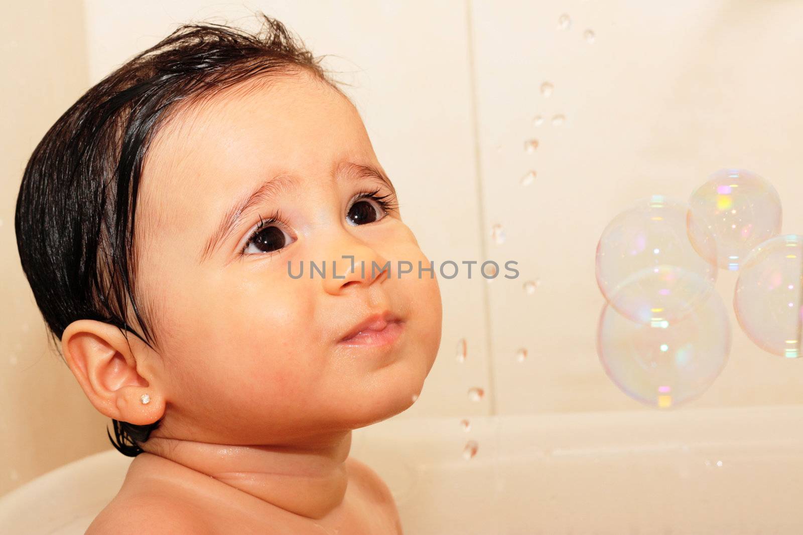 Adorable one-year old baby playing with foam in the bathroom by dacasdo