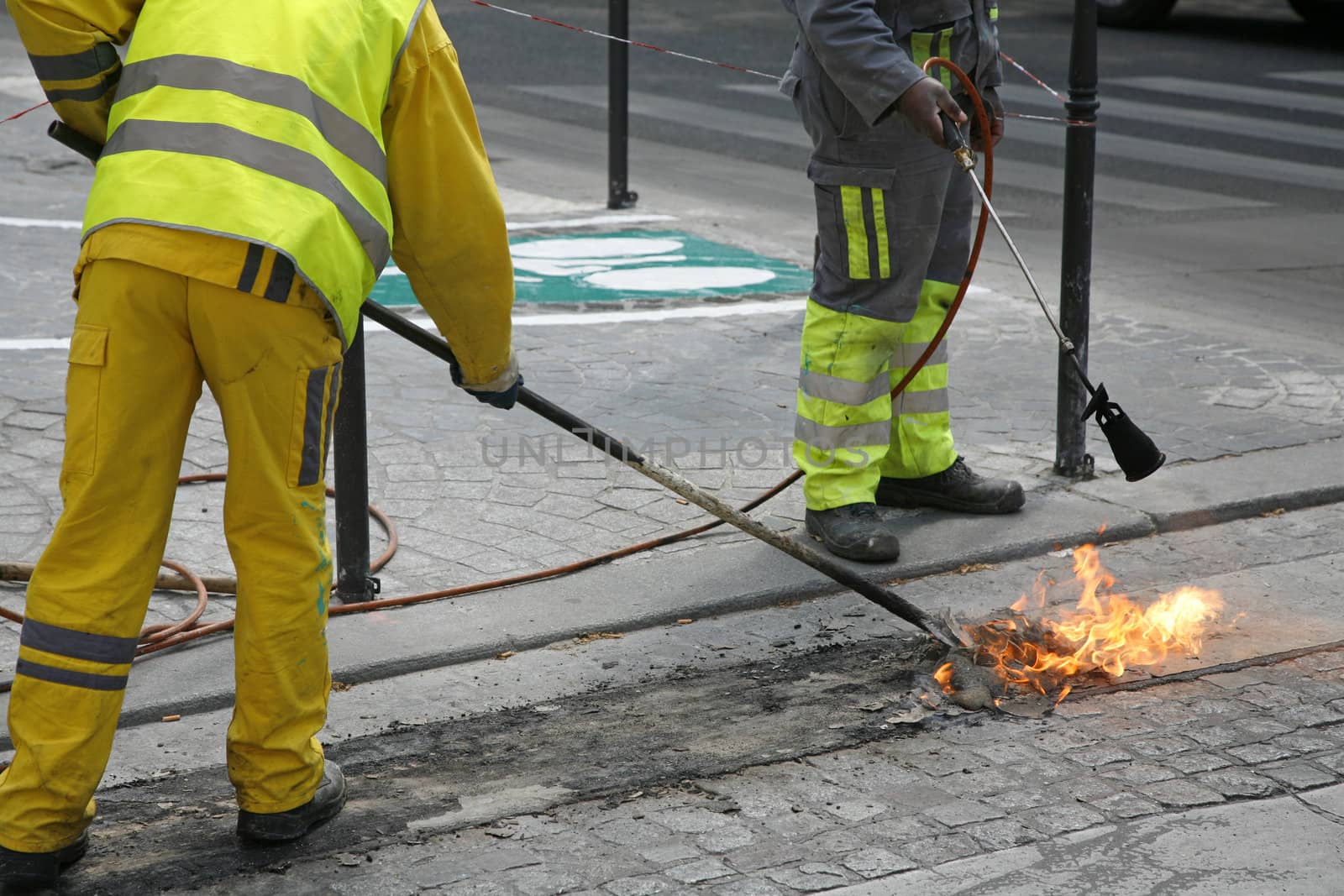 Worker burning old paint  in the streets of Paris, France.
