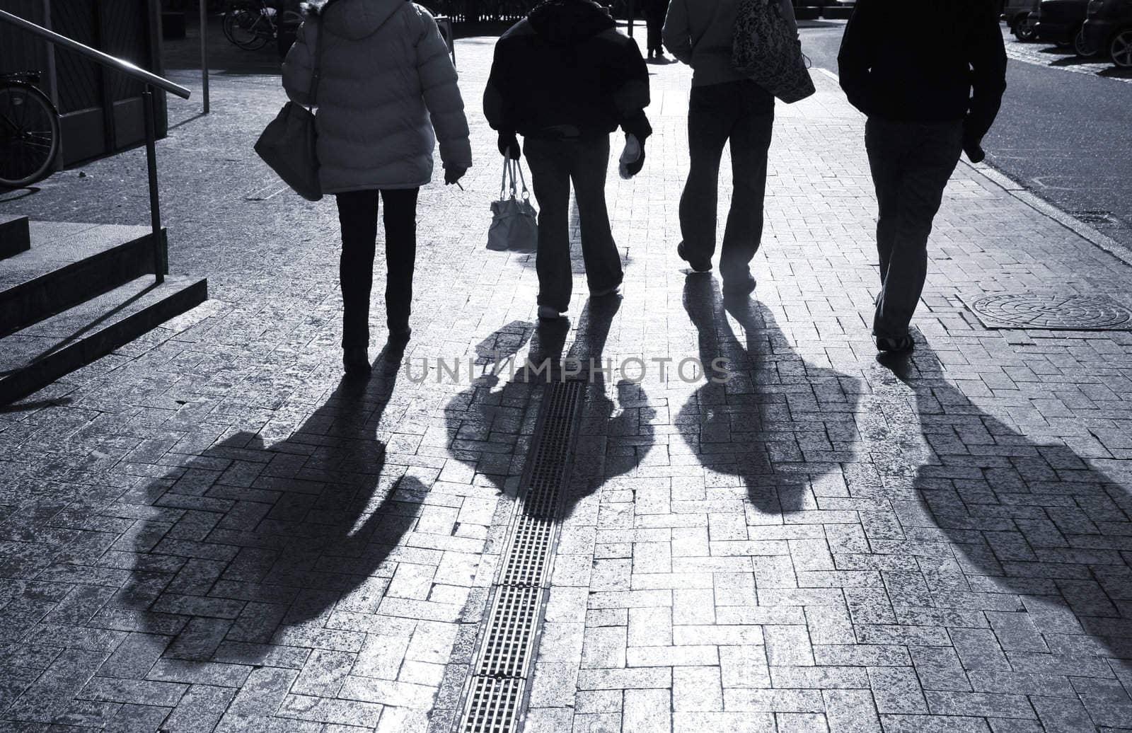 Commuters on way to job on a wet morning just after the sun broke through. Monochrome image.