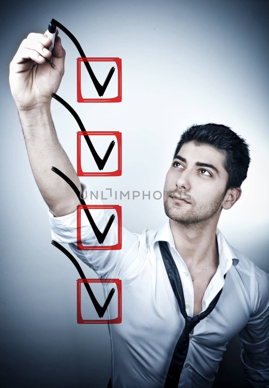 Young business man drawing a tick in a box on a glass board