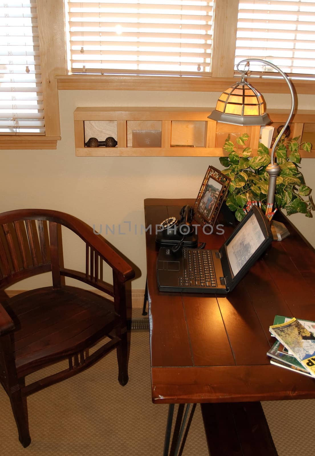 Small windowed home office with wooden desk and chair