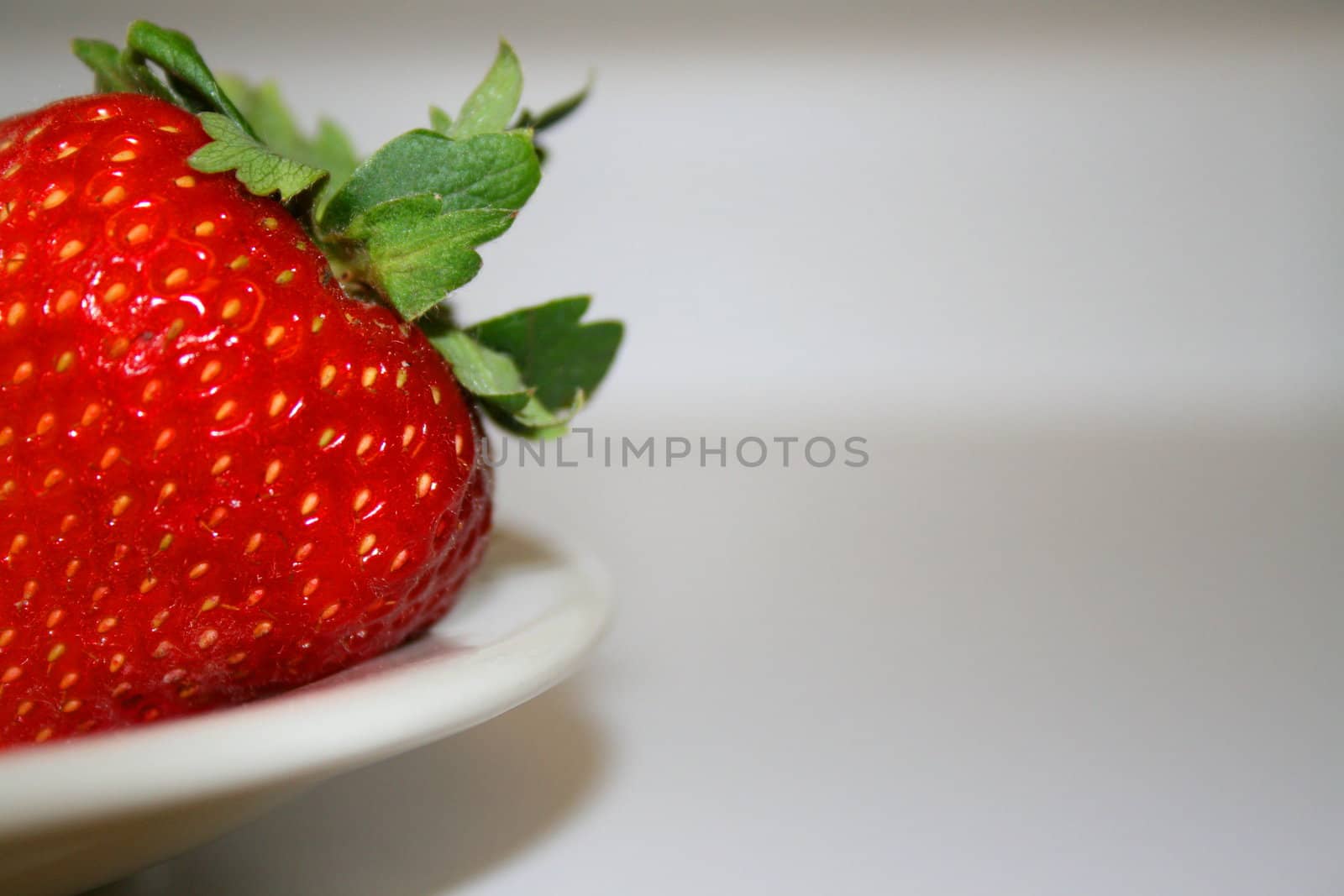 Close up of a ripe strawberry on a plate.
