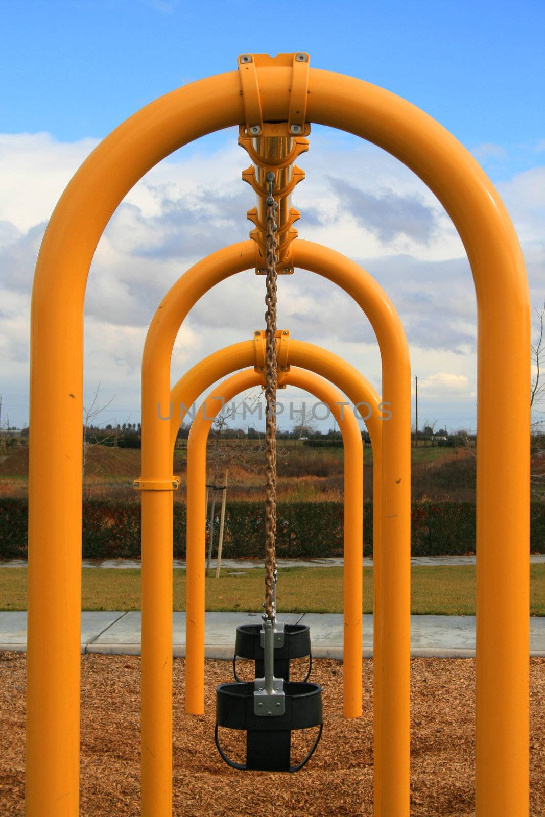 A row of swings in a playground.
