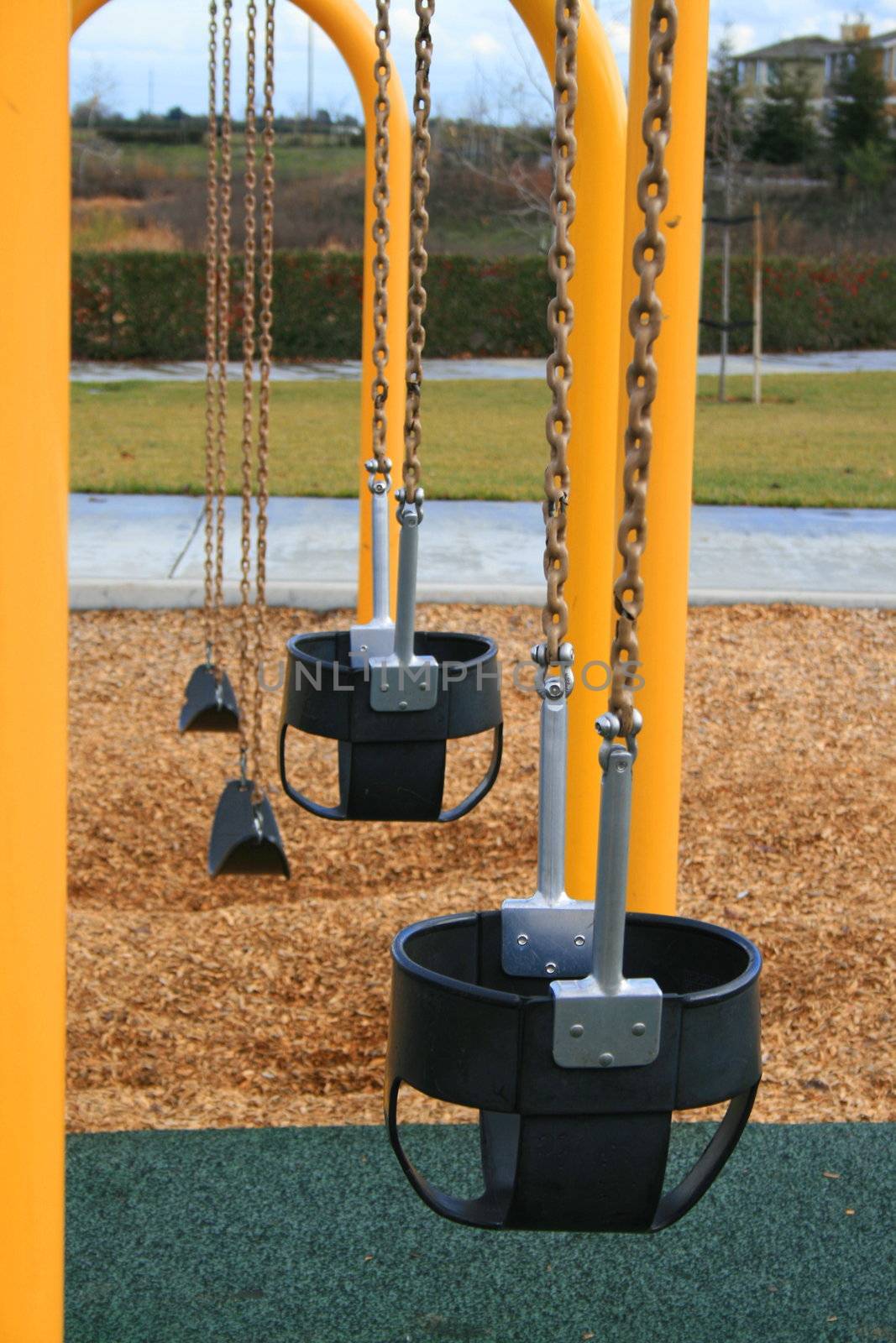 A row of swings in a playground.
