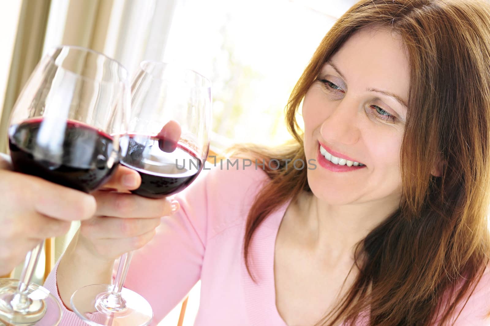 Mature woman toasting with red wine by elenathewise