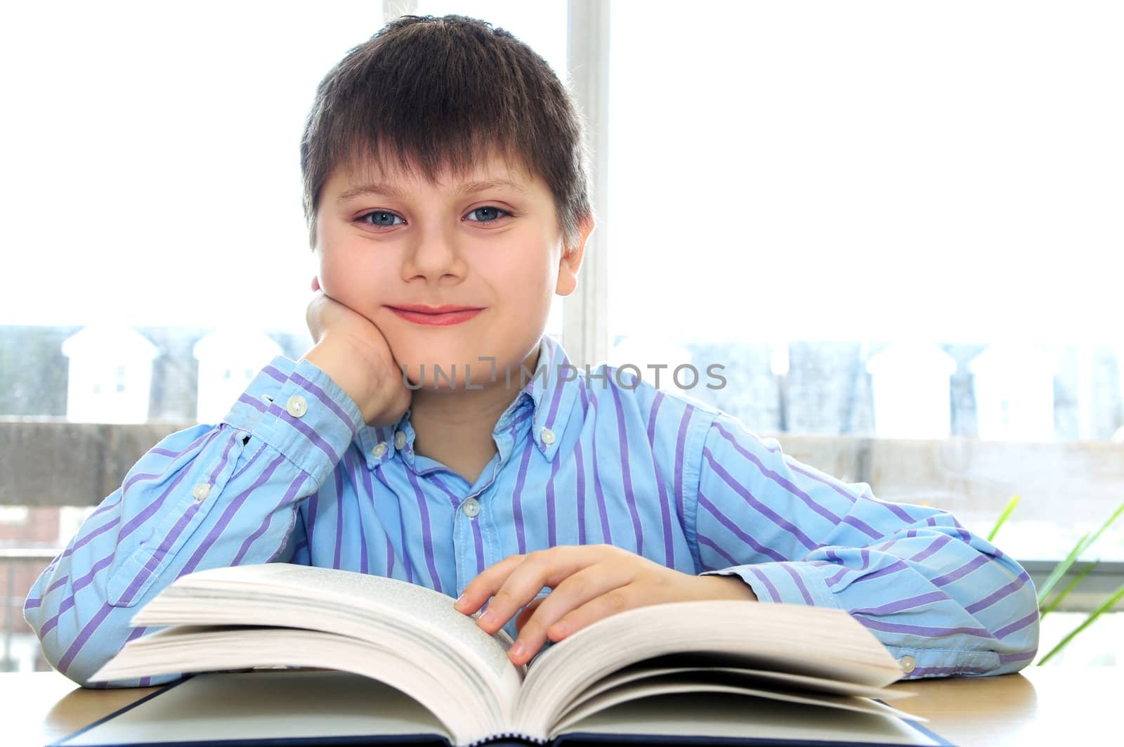 Happy school boy studying with a book