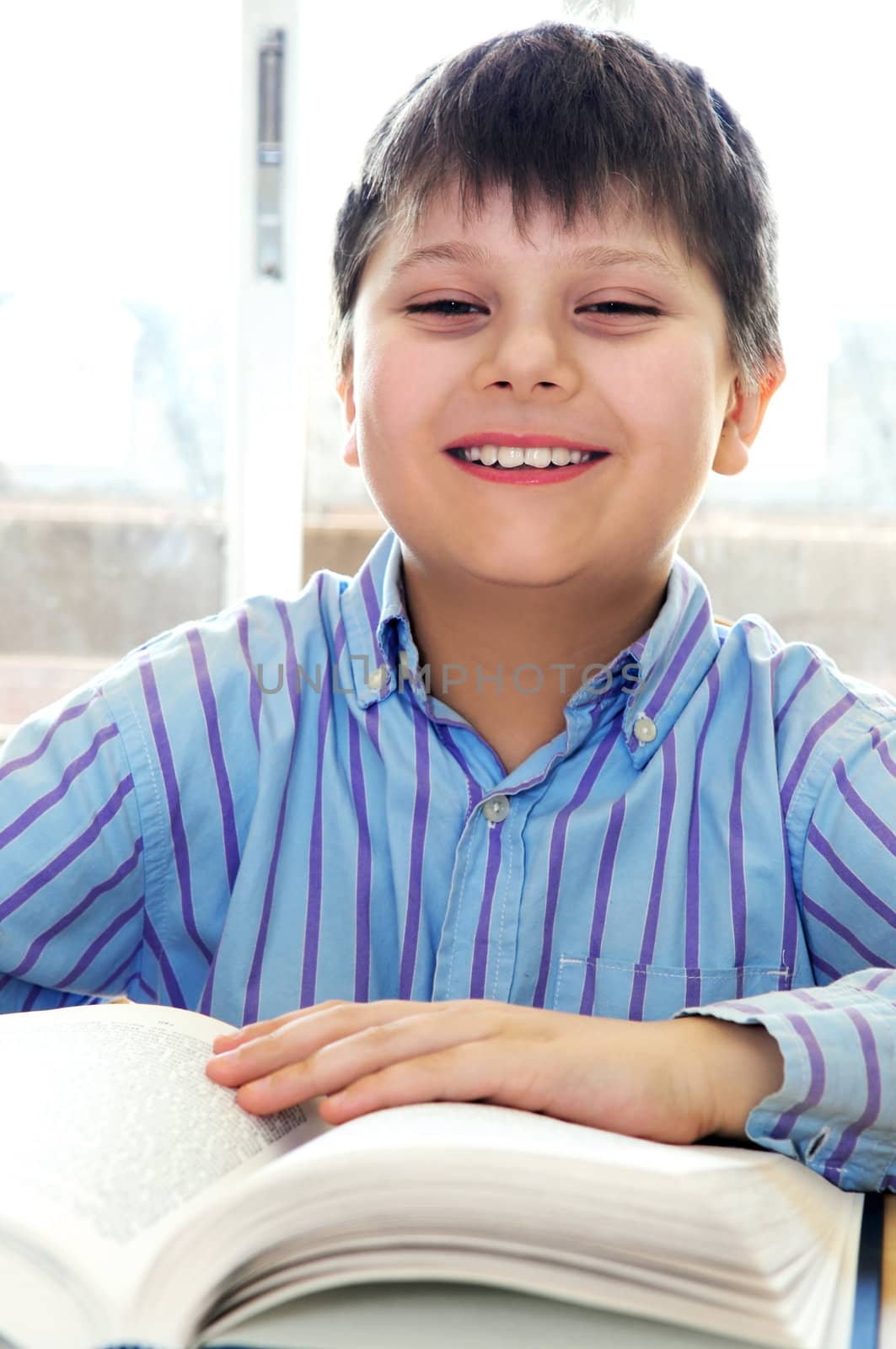 Happy school boy studying with a book