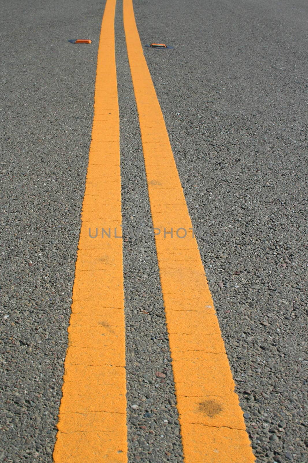 Close up of two yellow road lines.
