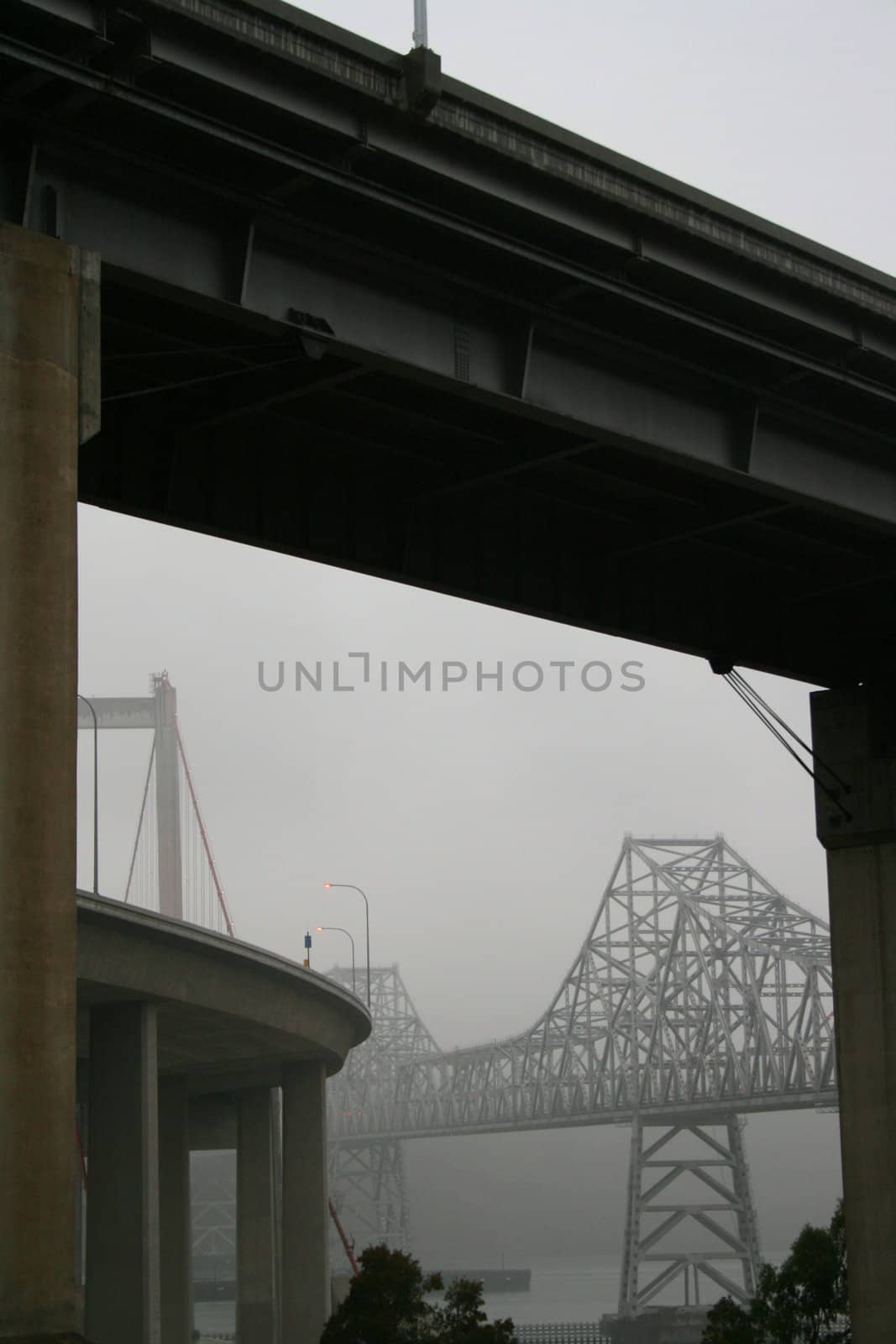 Two tall modern bridges in a fog.
