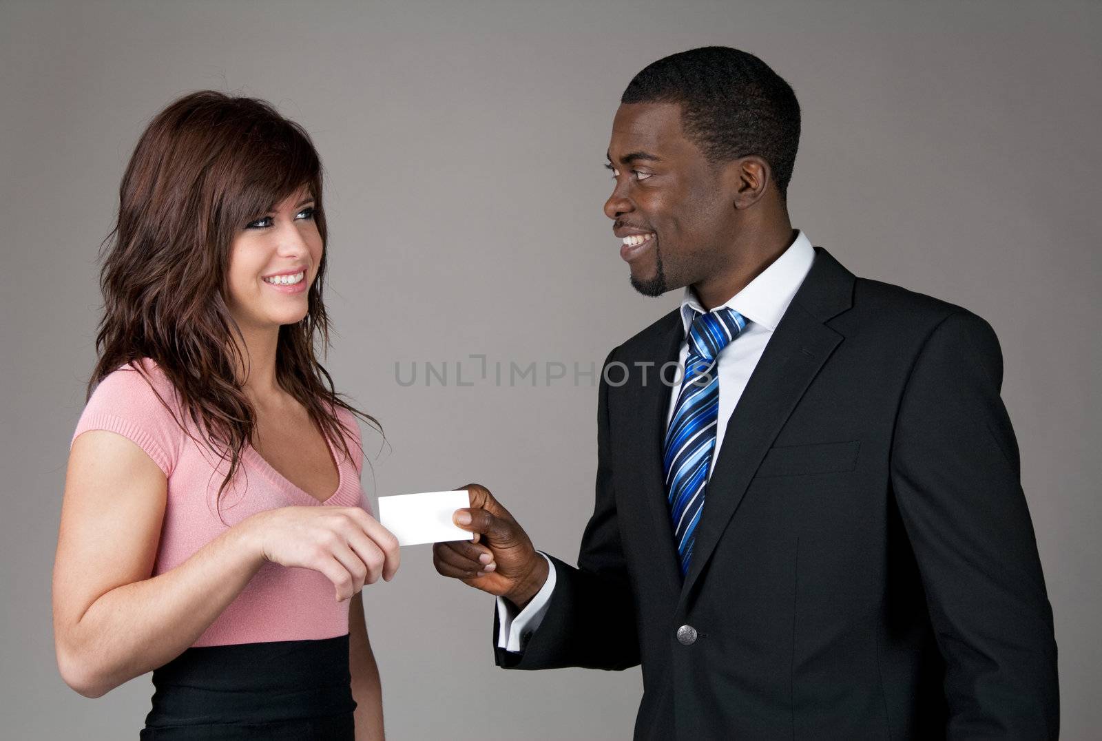 African American businessman giving his business card to a young Caucasian woman.