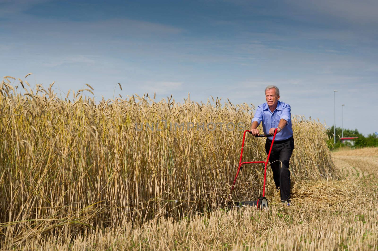 Senior businessman embarking on a new challenge as he starts to harvest his field of ripe golden grain using just a push type manual lawnmower filled with determination to succeed