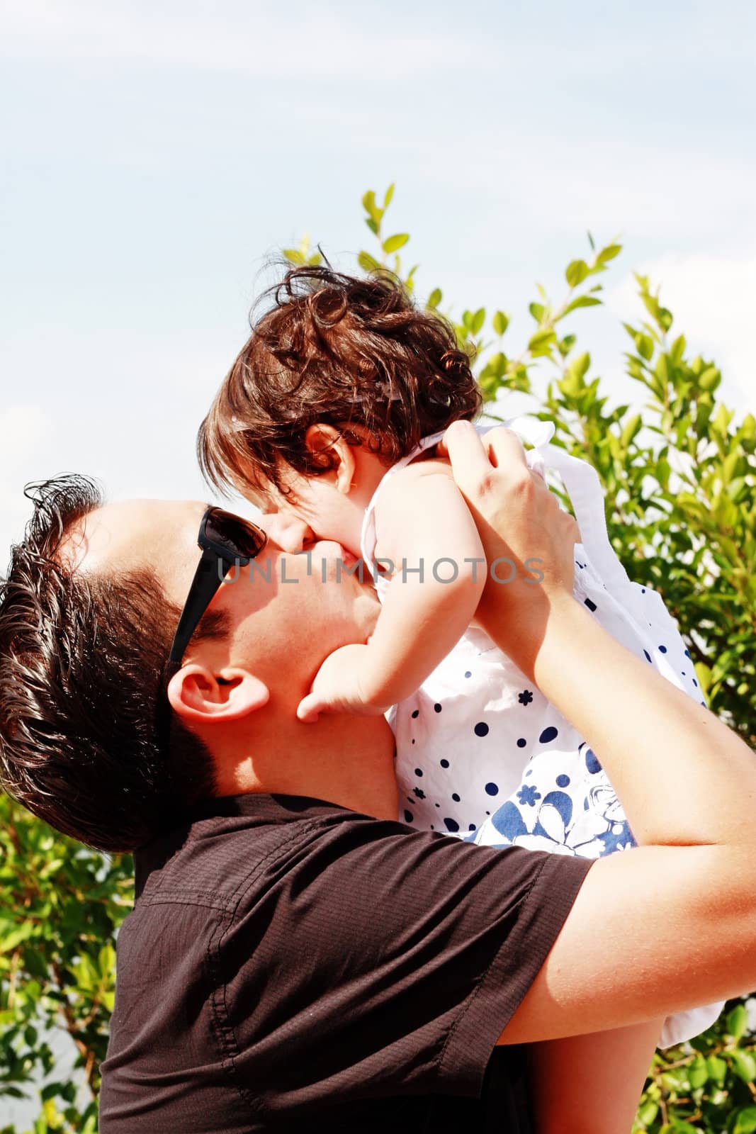 father in early thirties gives his son a kiss on the cheek in th by dacasdo