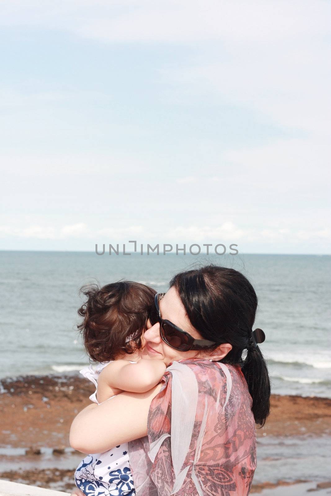 Mother hugging her baby over sea by dacasdo