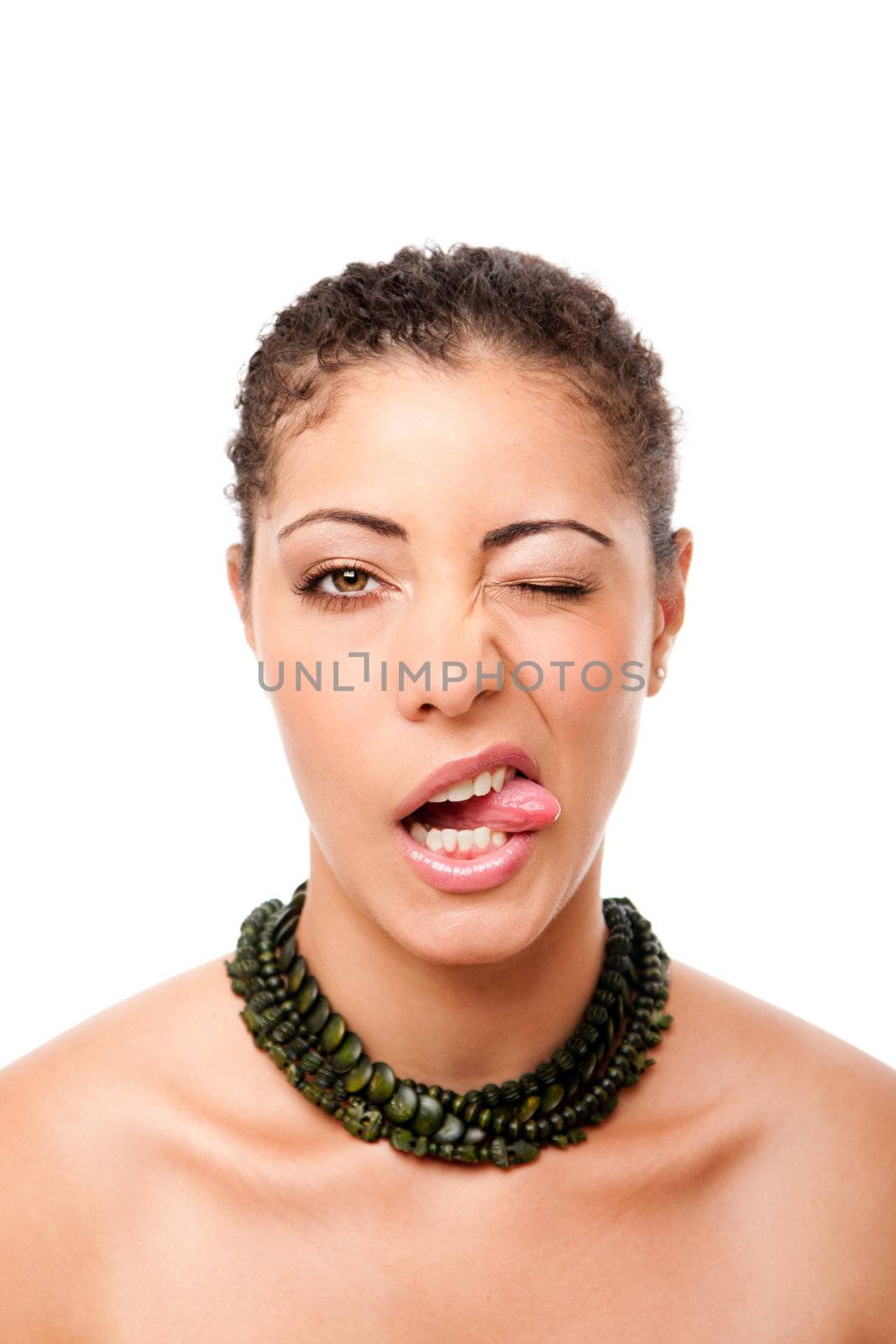 Funny face of a beautiful attractive fashion model sticking out tongue while winking, wearing green necklace, isolated.