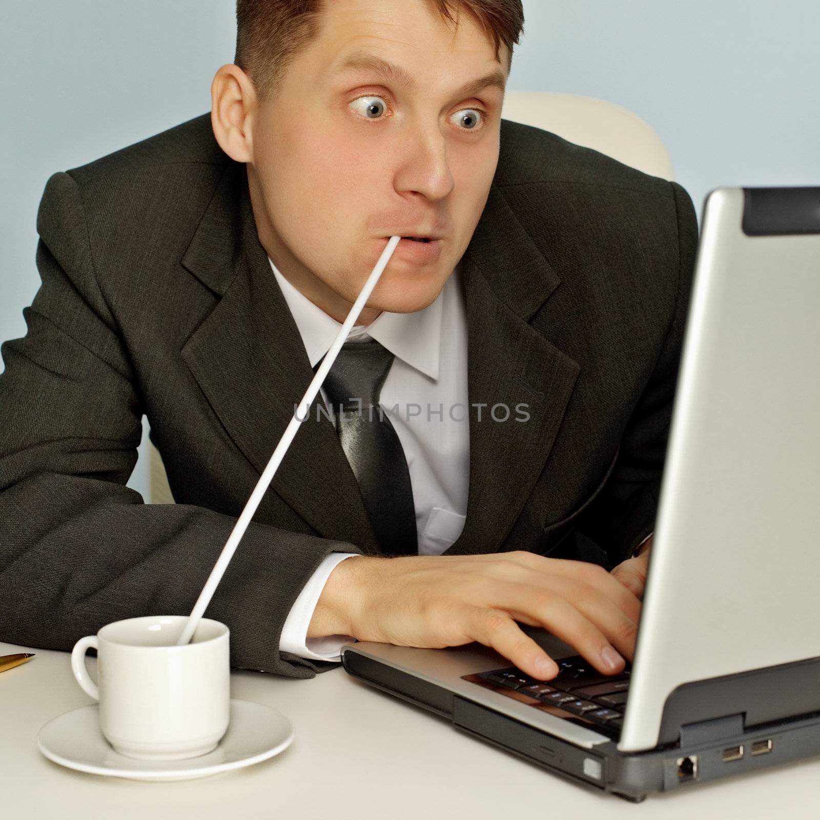 Funny businessman drinking hot coffee and working on the Internet