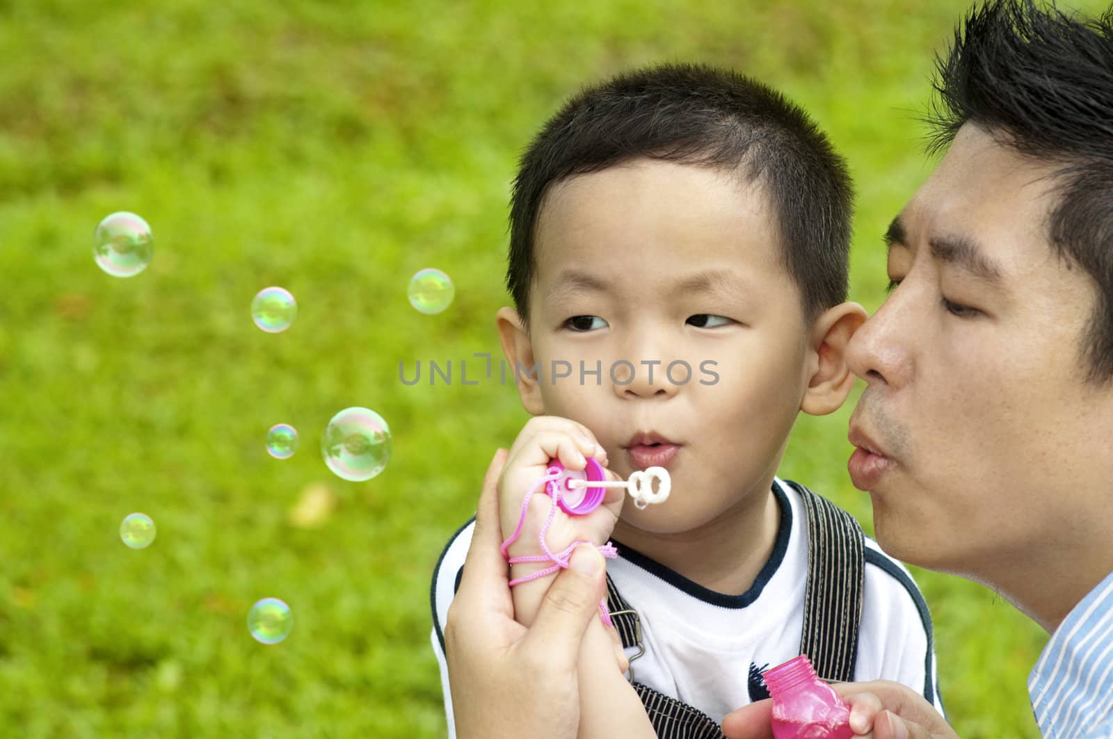 Asian father and son blowing bubbles outdoor