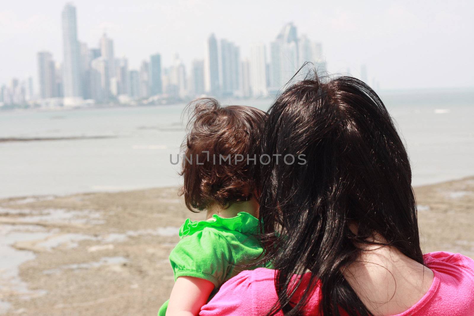 Mother indicates her baby something interesting in sea