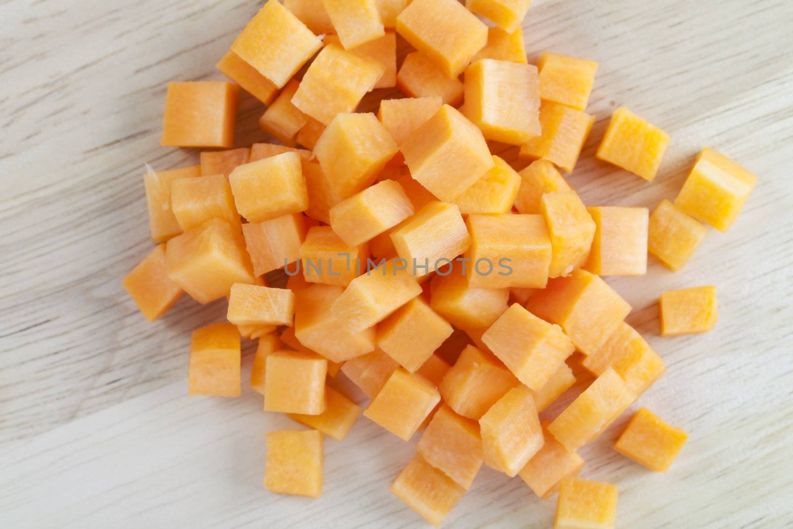 Brunoise or cubed carrots on wooden surface.