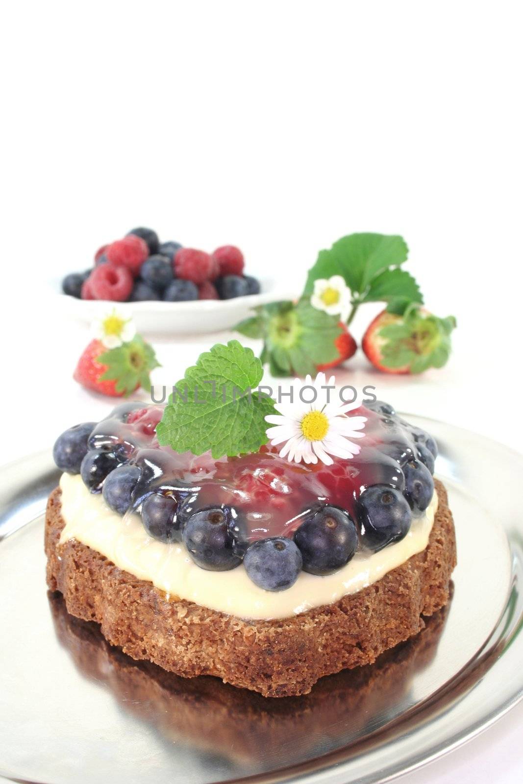 heart-shaped fruit tart with forest berries, lemon balm and daisies