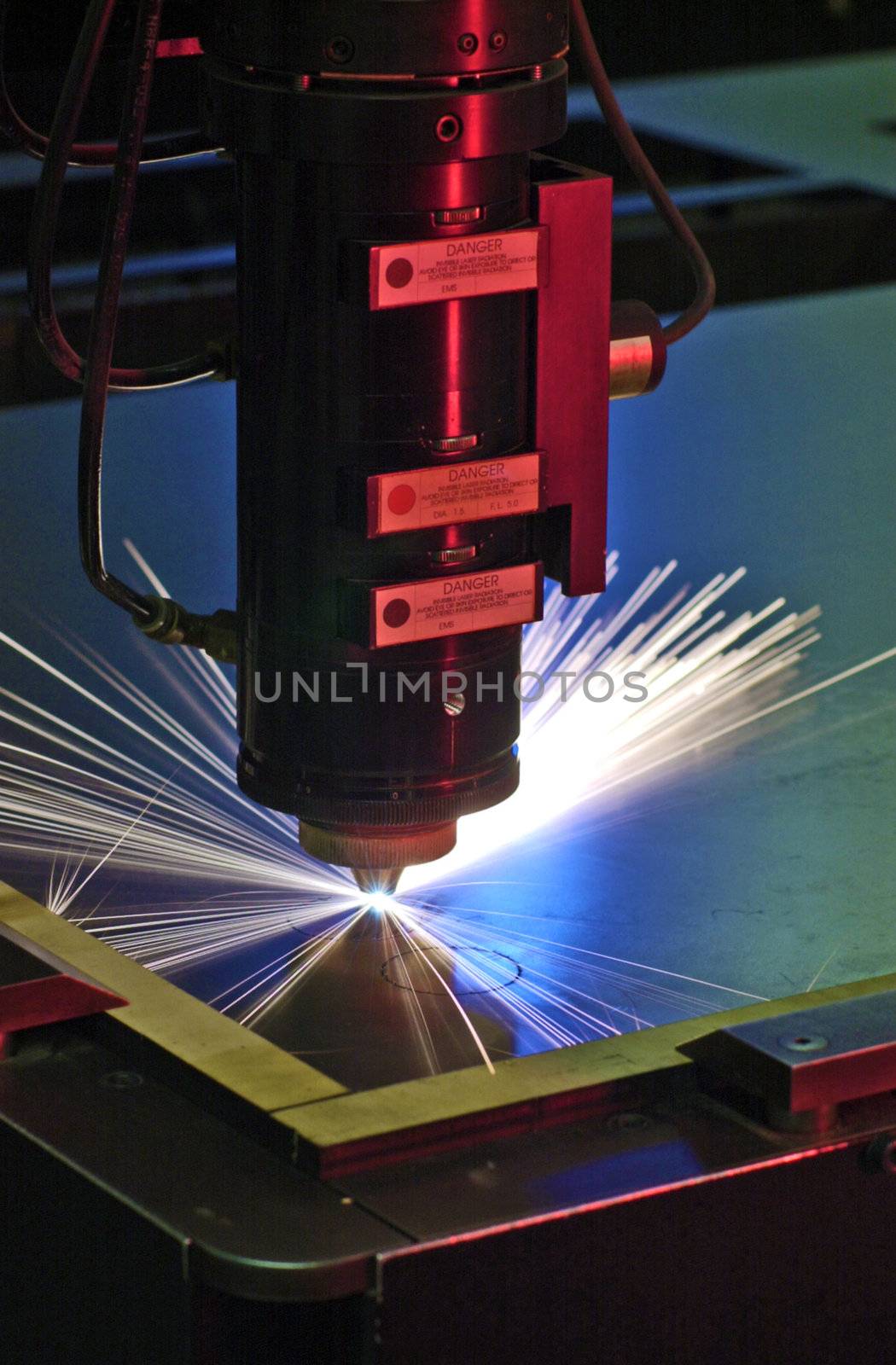 Industrial laser cutter with blue and red background, with sparks