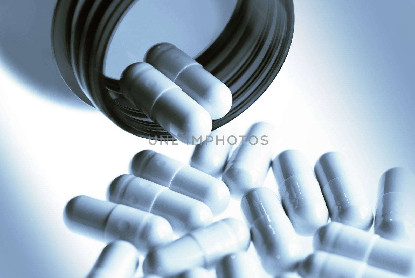 Pills spilling out of pill bottle in blues