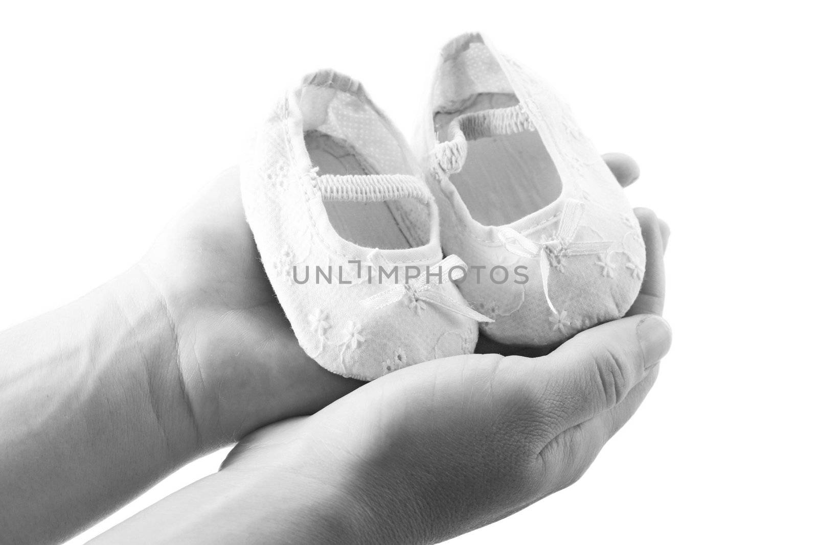 Hands holding newborn baby shoes by dacasdo