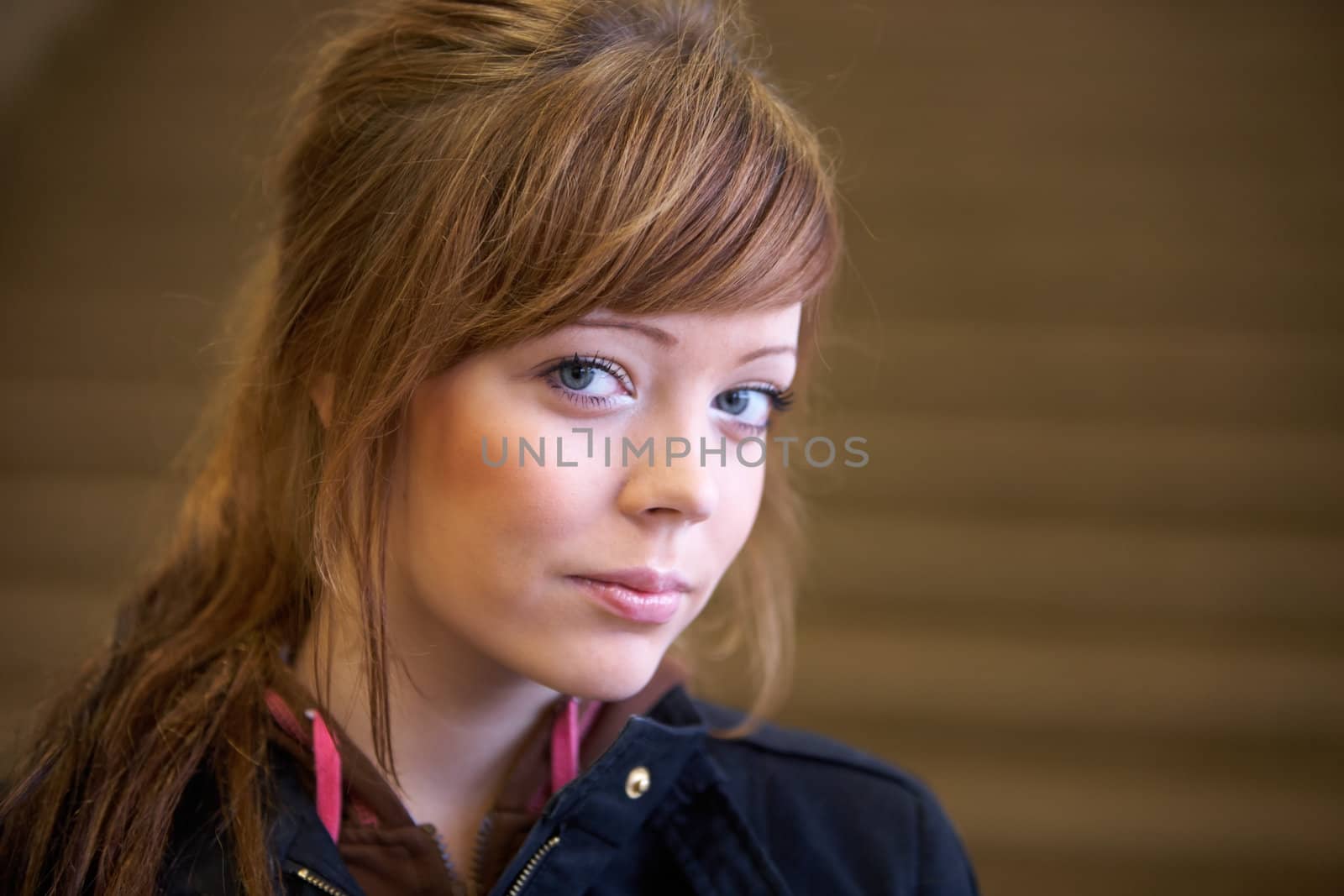 Teenage girl by staircase indoors, looking at camera