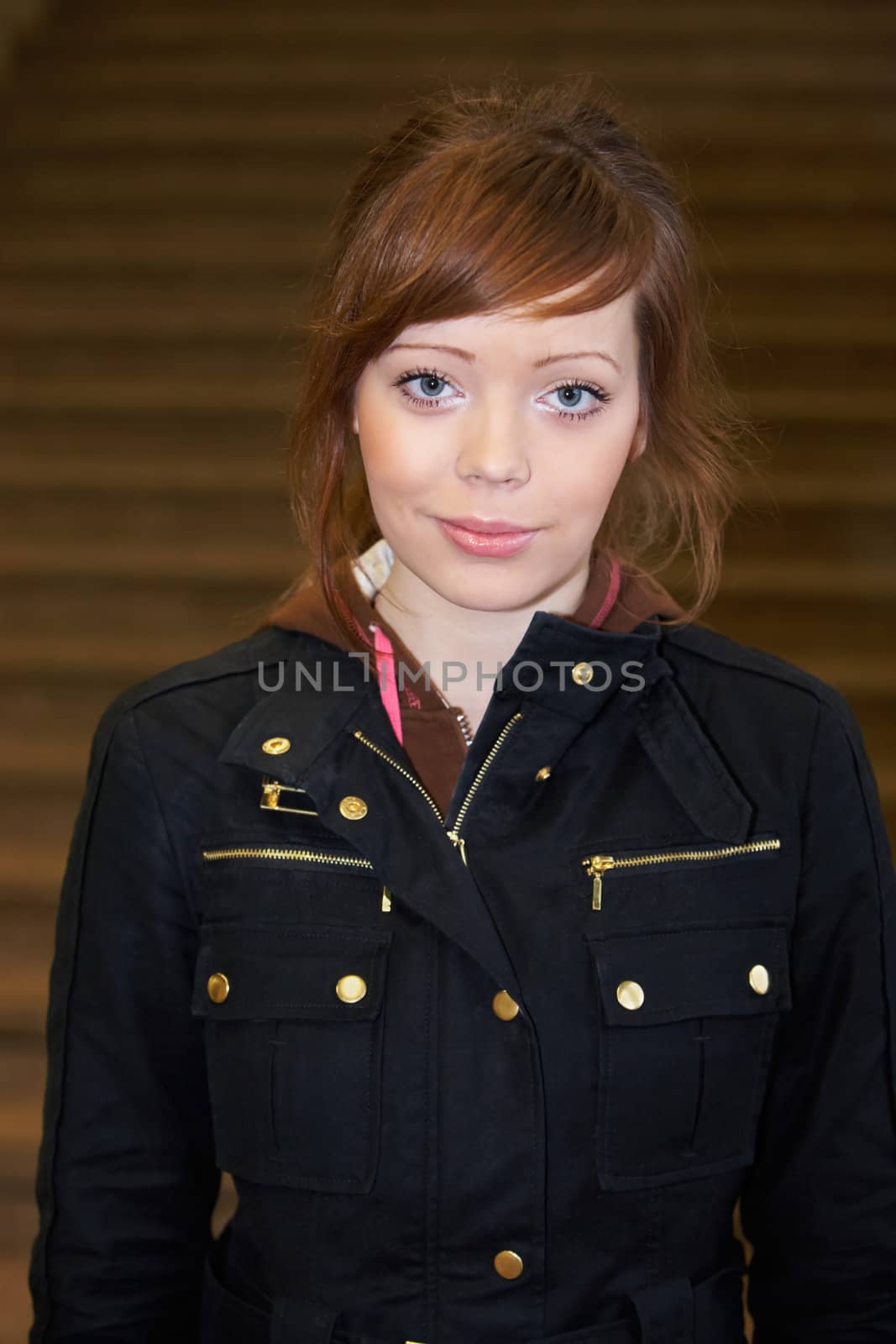 Teenage girl by staircase indoors, looking at camera