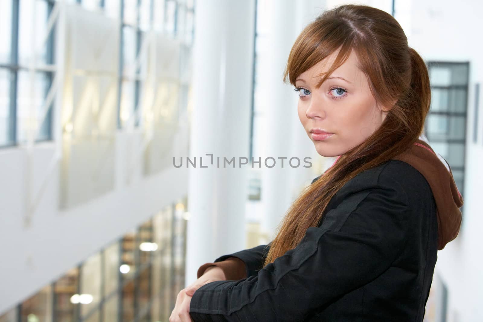 Teenage girl in modern building, looking at camera