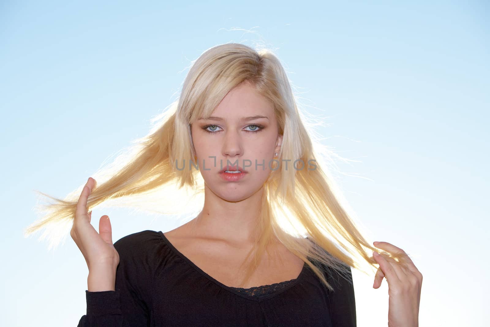 Teenage girl holding her hair, backlit
