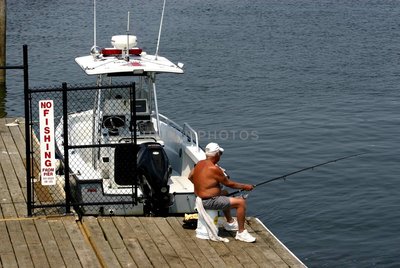 Man fishing on pier next to NO FISHING sign