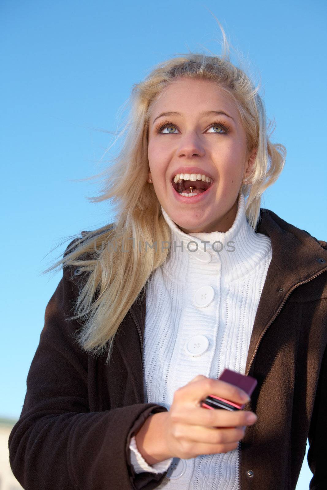 Teenage girl holding mobile phone, laughing