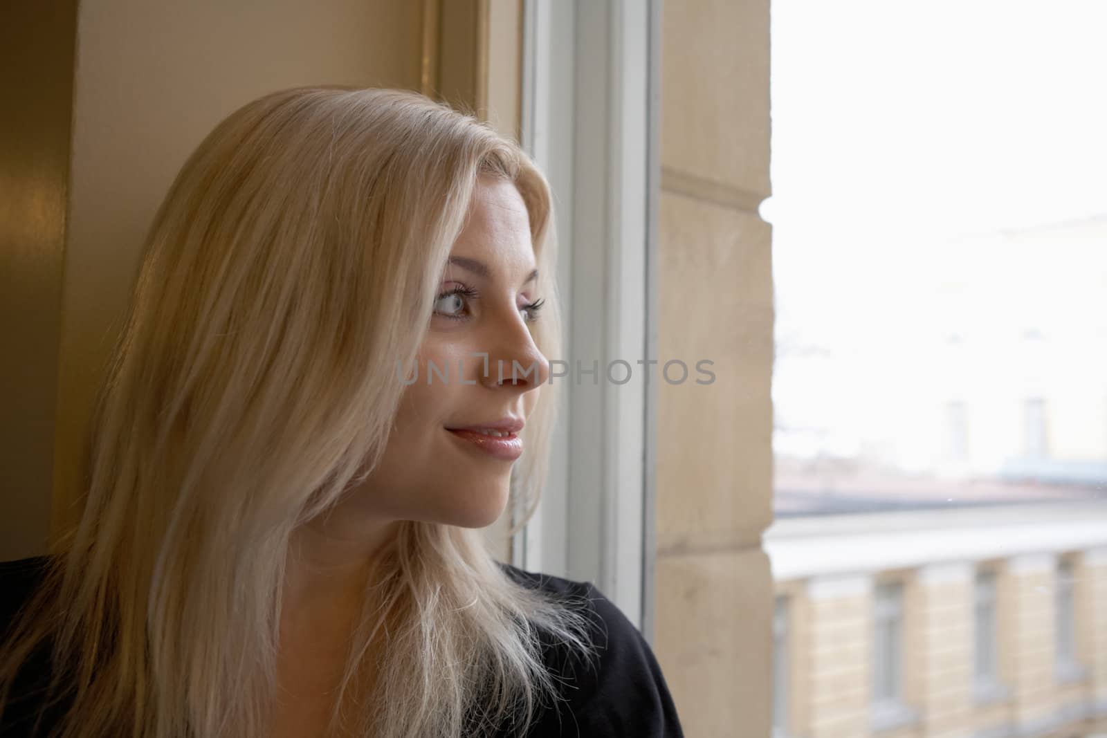 Young woman looking out window, smiling