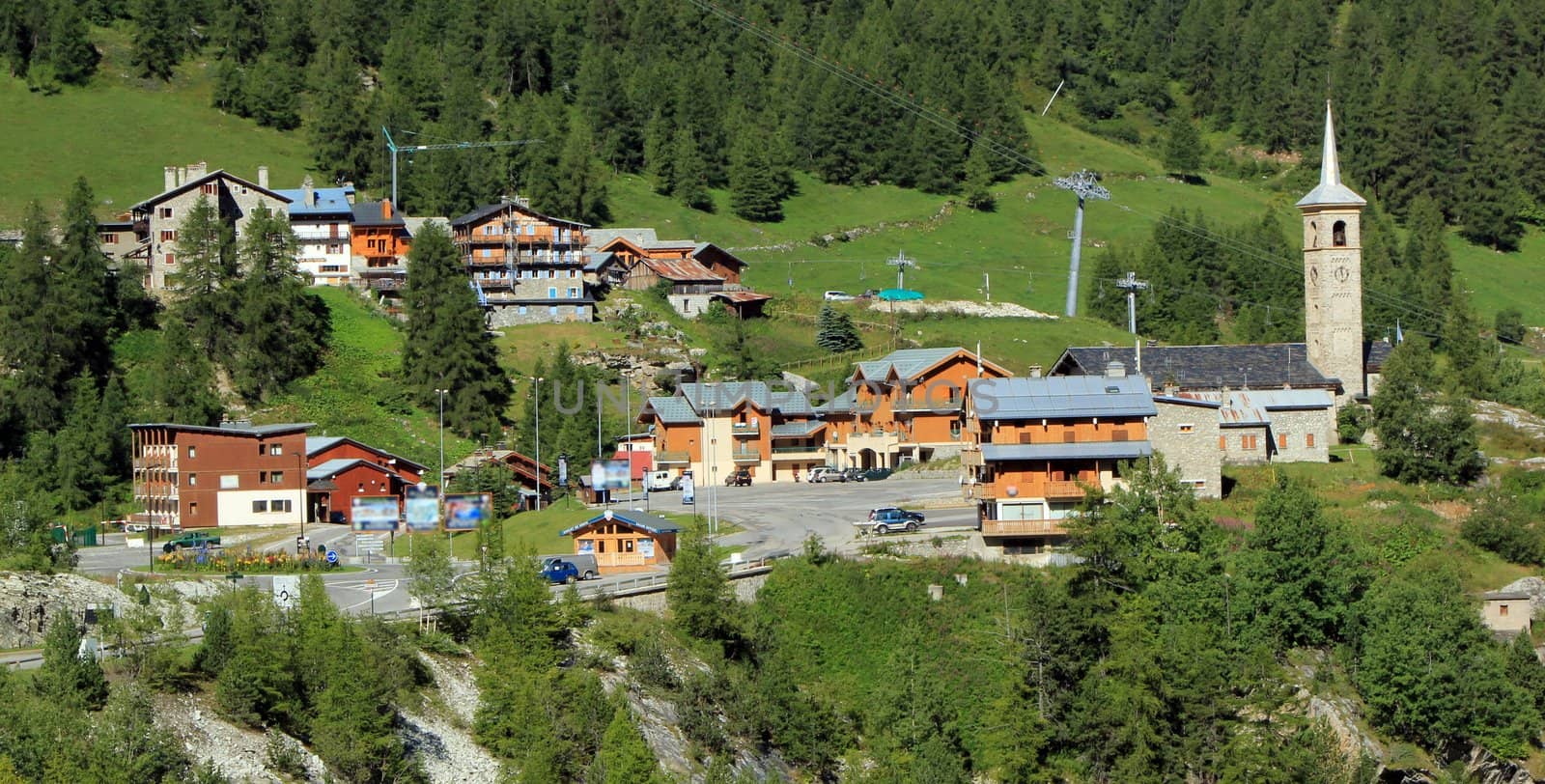 View of Tignes village in the Alps mountains with its houses and church among fir trees, France