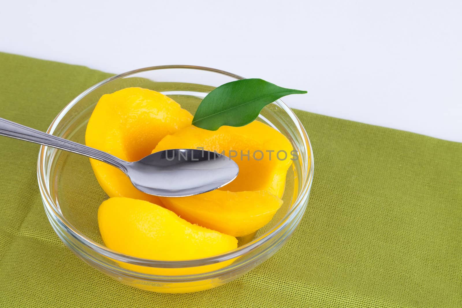 Opened jar with halves of peaches in sweet syrup.