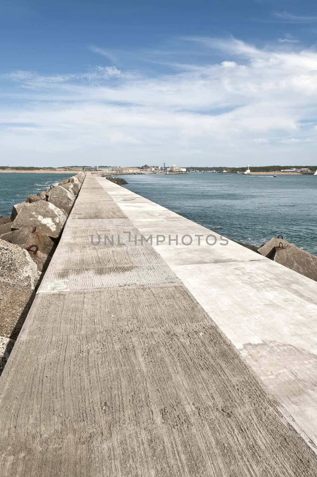 Long concrete jetty with quiet sea and blue sky
